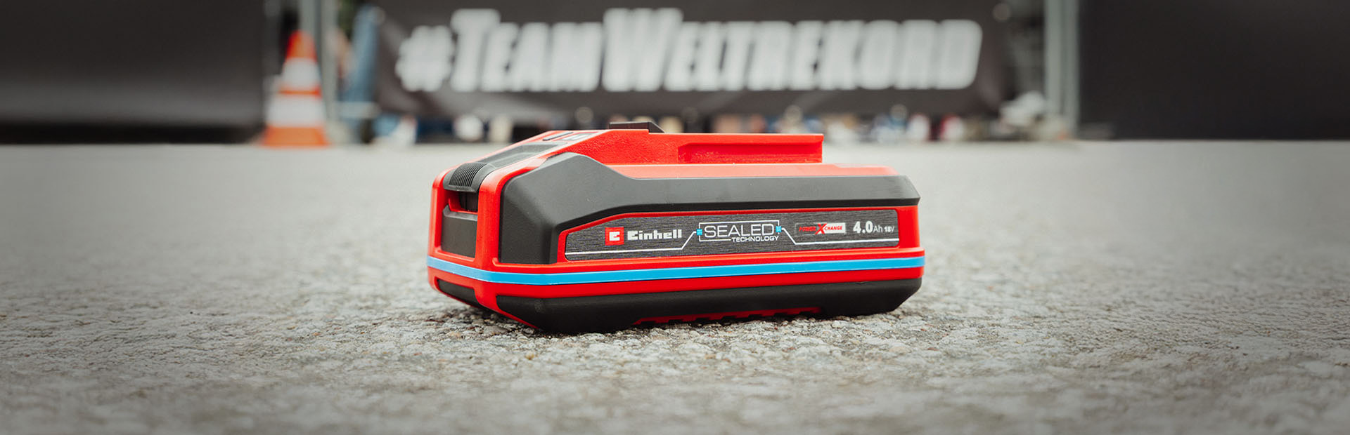 Einhell SEALED battery Power X-Change 4.0 Ah lies on asphalt.