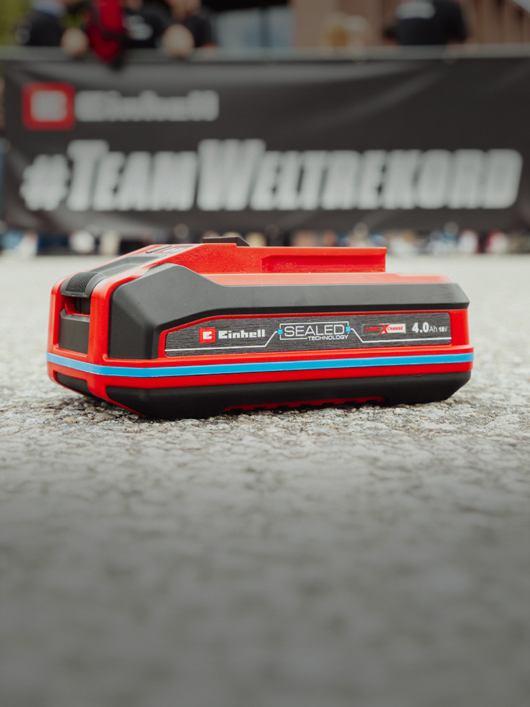 Einhell SEALED battery Power X-Change 4.0 Ah lies on asphalt.