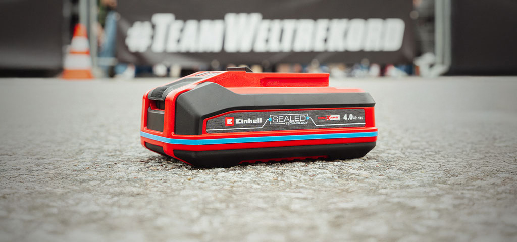 Einhell SEALED battery Power X-Change 4.0 Ah lies on asphalt.