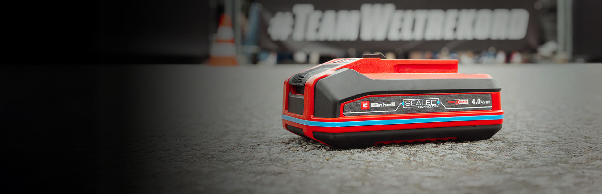 Einhell SEALED battery Power X-Change 4.0 Ah lies on asphalt.