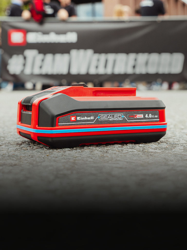 Einhell SEALED battery Power X-Change 4.0 Ah lies on asphalt.